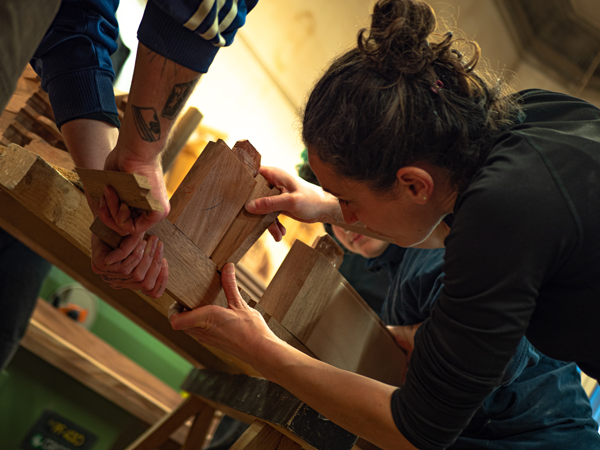 Apprenti menuisier en train de raboter une planche de bois massif dans l'atelier historique de la Philomathique de Bordeaux.