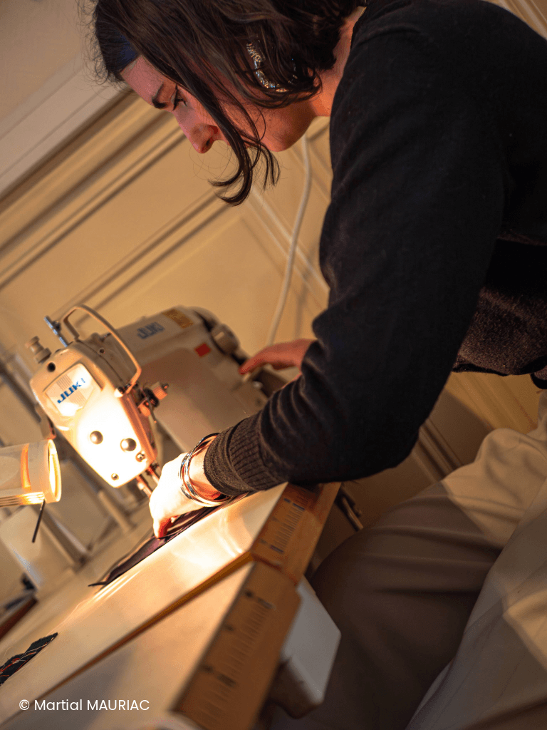 Une apprenante de la Philomathique en pleine session de couture sur une machine professionnelle lors d'une formation aux métiers de la mode.