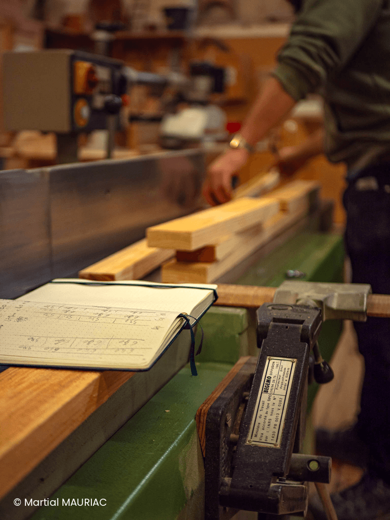 Apprenant réalisant une coupe de précision sur une pièce de bois massif dans les ateliers de la Philomathique à Bordeaux.