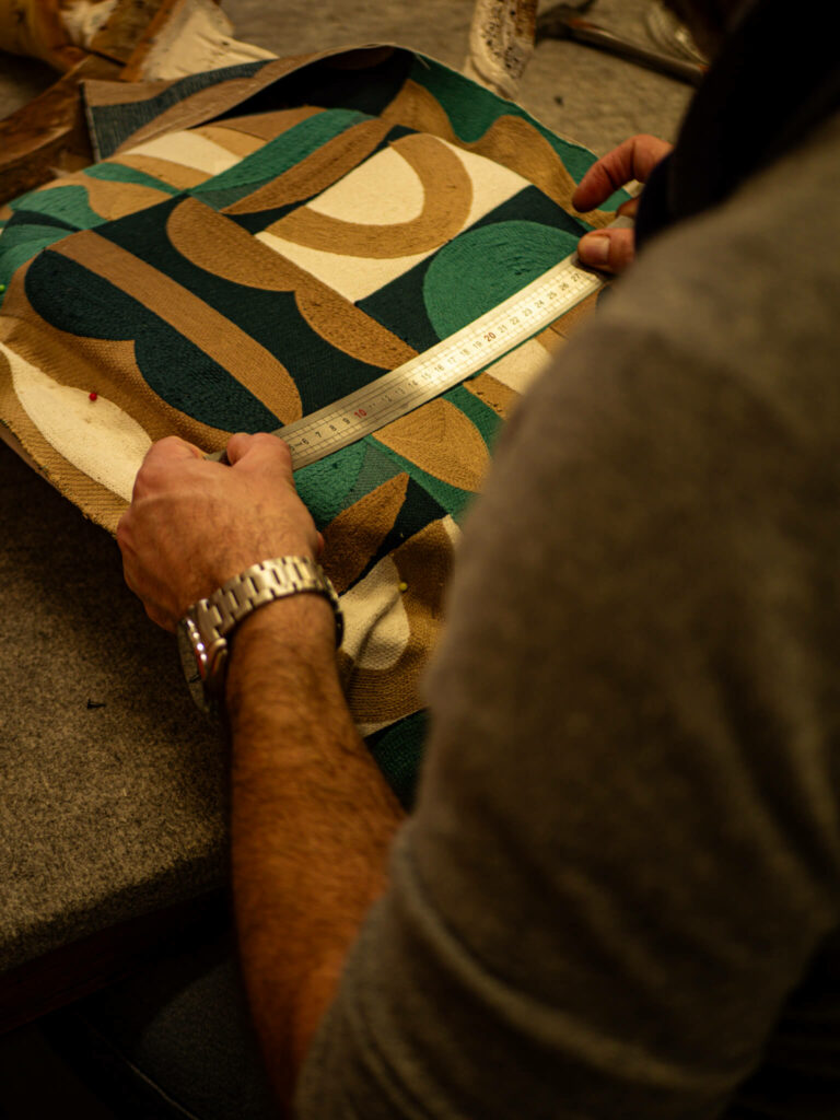 Un formateur expert en tapisserie d'ameublement à la Philomathique de Bordeaux prenant les mesures d'un fauteuil ancien lors d'un cours professionnel.
